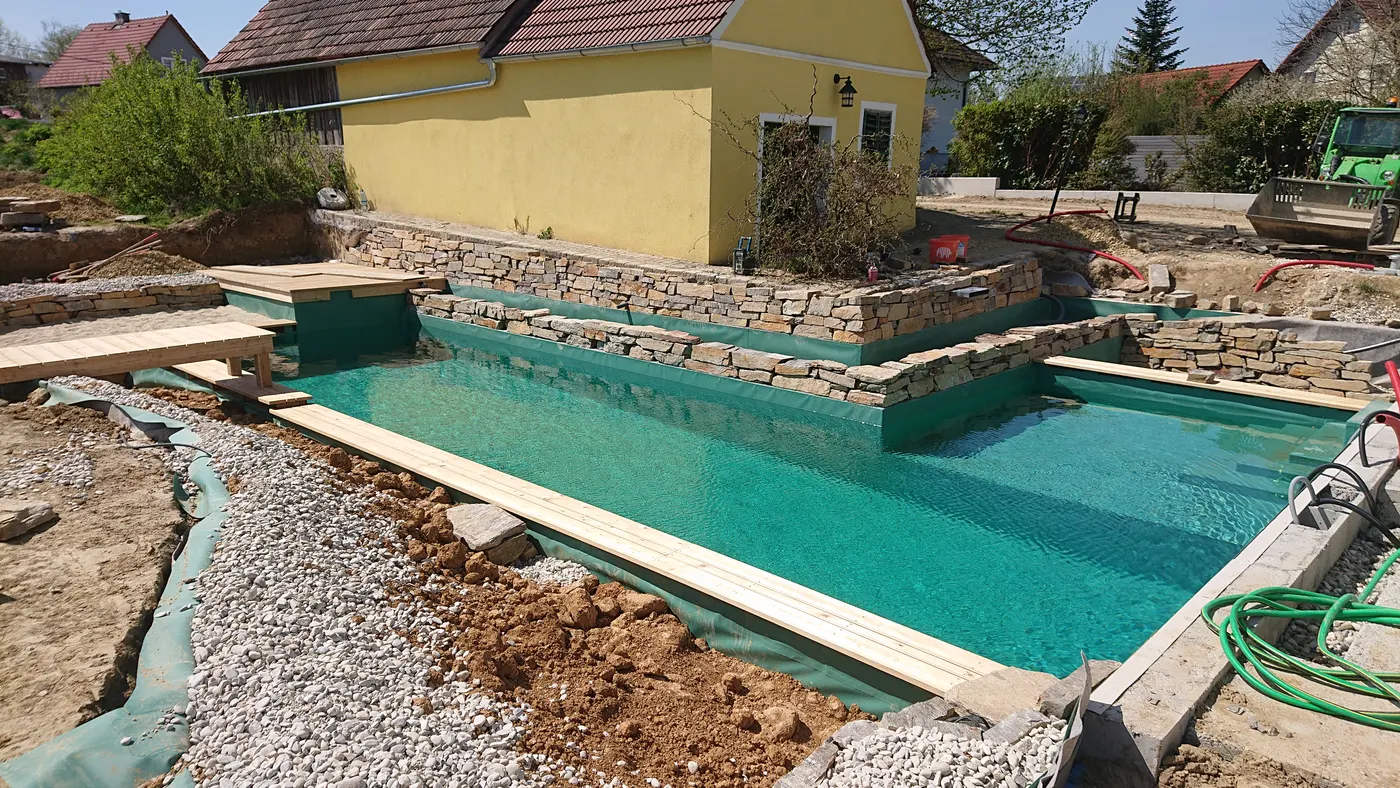 Schwimmbereich mit Natursteinmauer und Holzsteg
