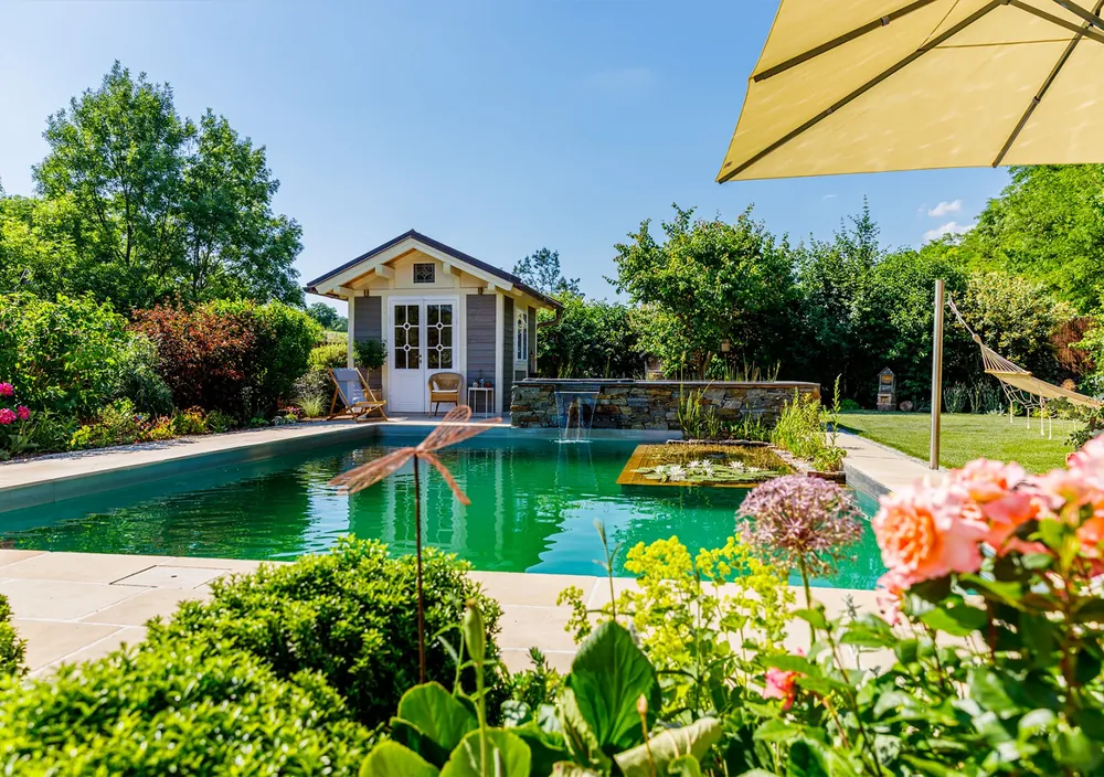 http://Naturpool%20mit%20Gartenhaus,%20Sonnenschirm%20und%20Blumenbeet