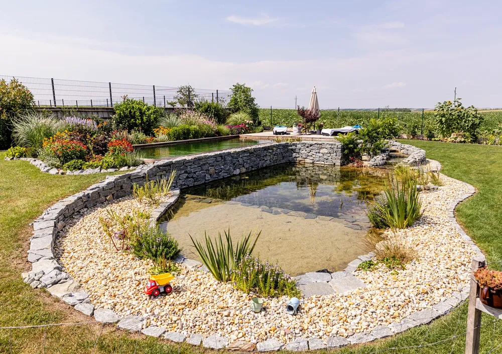 http://Schwimmteich%20mit%20Natursteinmauer,%20Kiesufer%20und%20Staudenbeet%20im%20Weinviertel