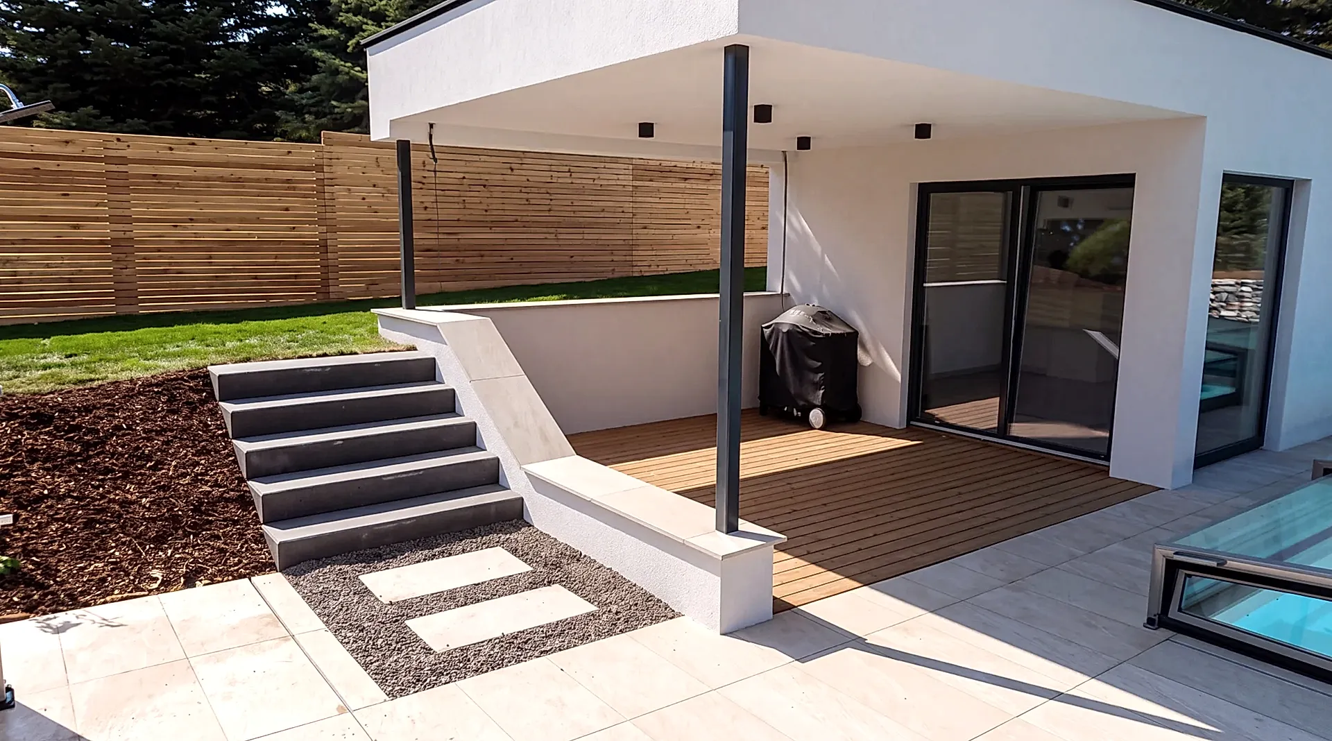 Terrasse unter einem verglasten Anbau, davor Lavendel und Ziergräser