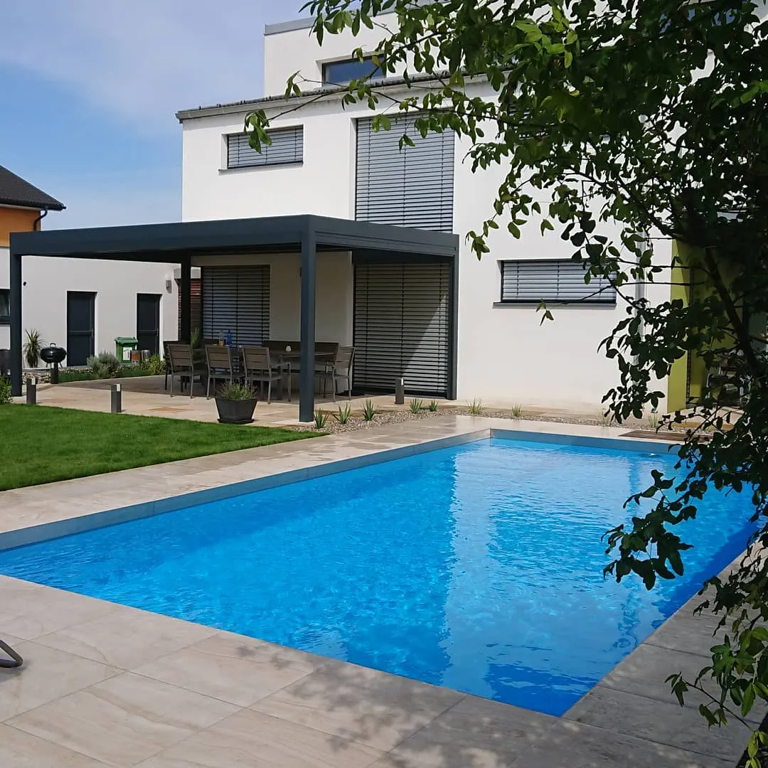 Pool mit breitem Holzdeck und großformatigem Plattenrand am Haus