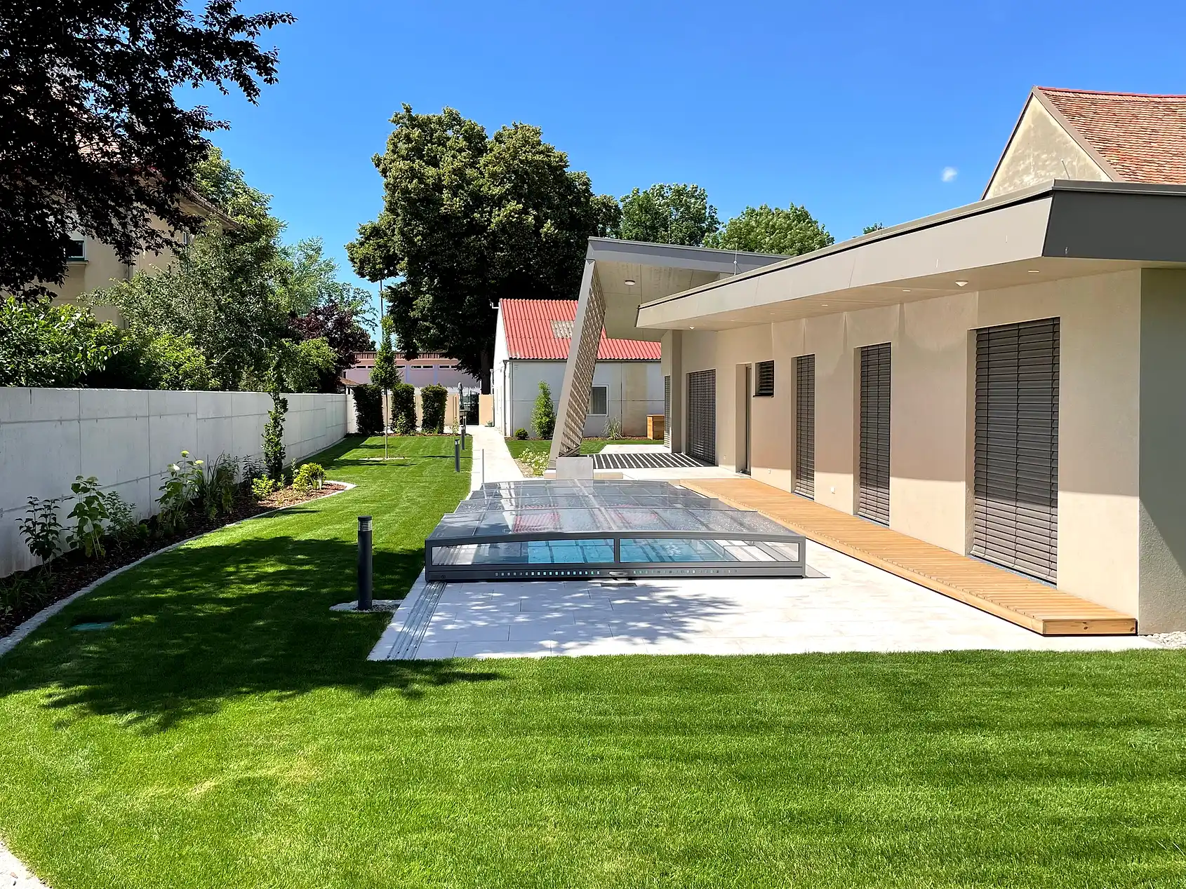 Pool mit Rasenfläche und Sitzplatz neben einem modernen Wohnhaus