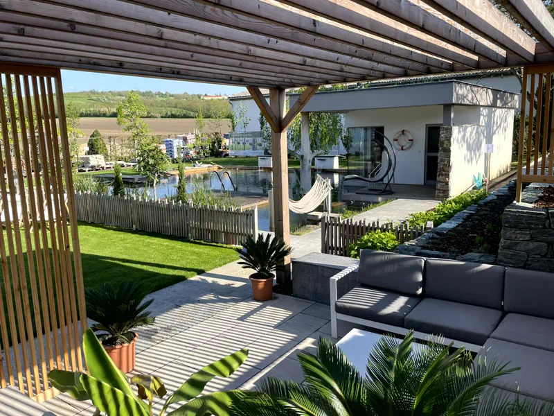 Überdachte Terrasse mit Lounge-Möbeln und Holzlamellen am Schwimmteich