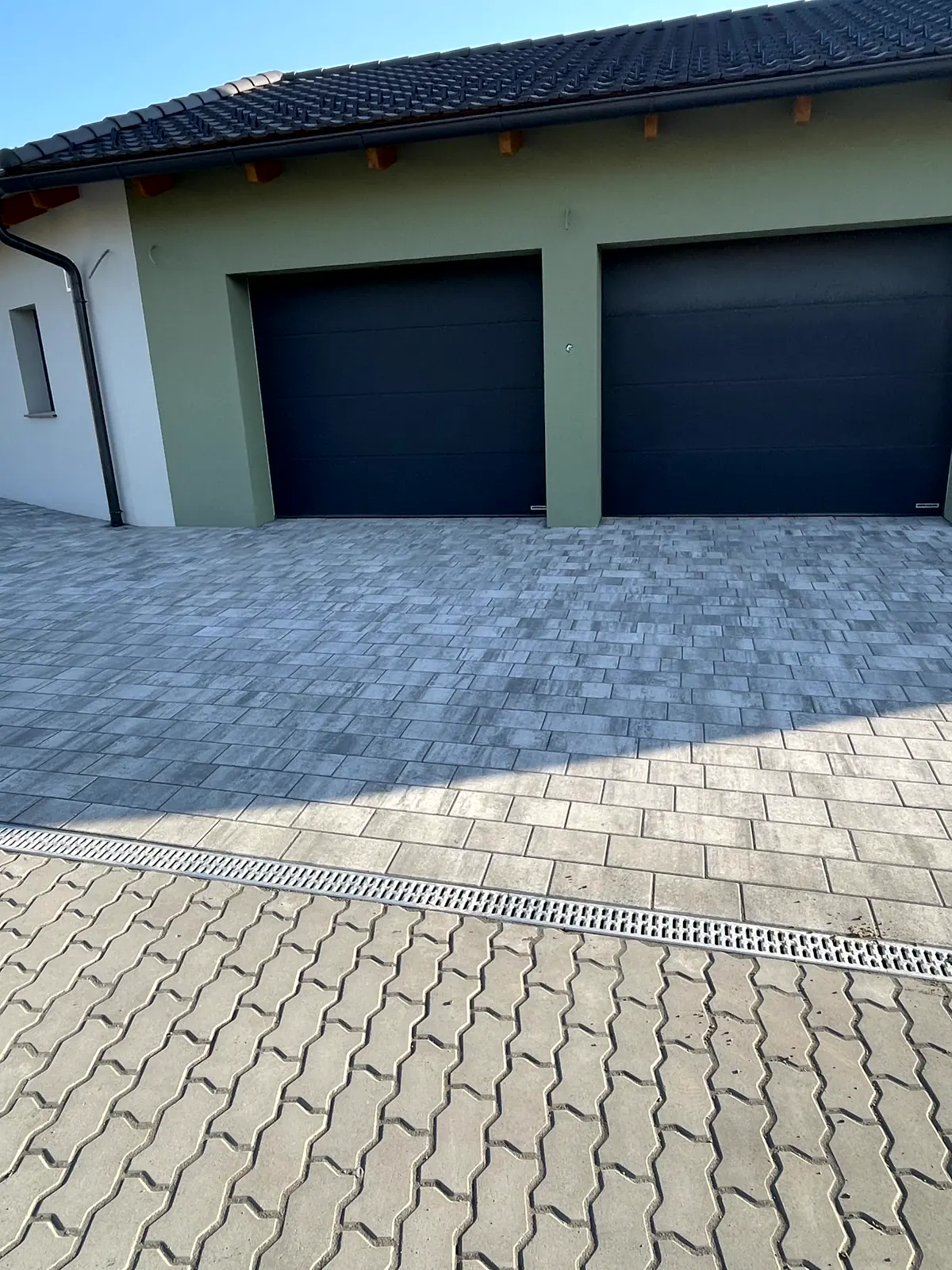 Gepflasterte Zufahrt mit Rasengittersteinen und Entwässerungsrinne vor einer Doppelgarage