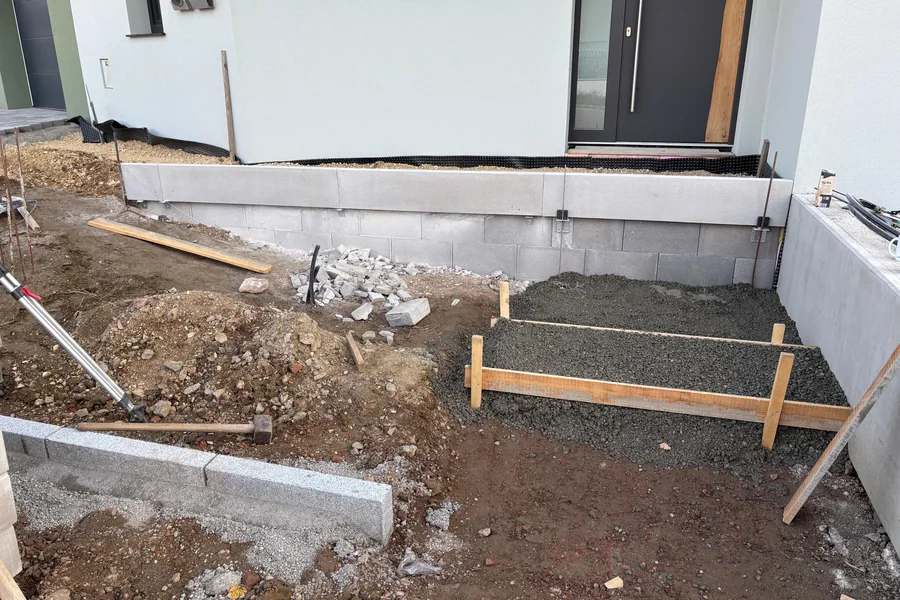 Betonstufen in der Schalung vor dem Hauseingang, daneben der verdichtete Unterbau