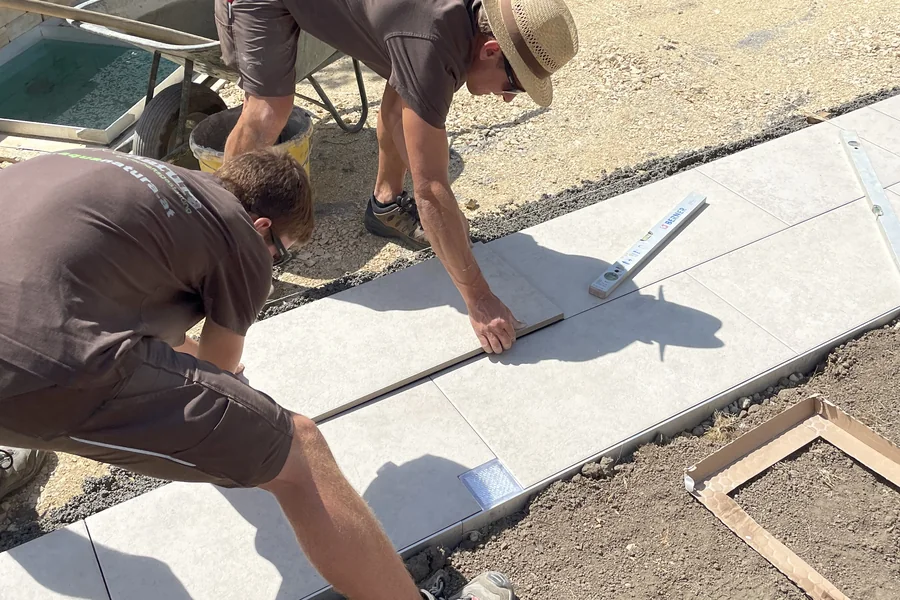 Zwei Mitarbeiter verlegen großformatige Platten auf Richtschnur
