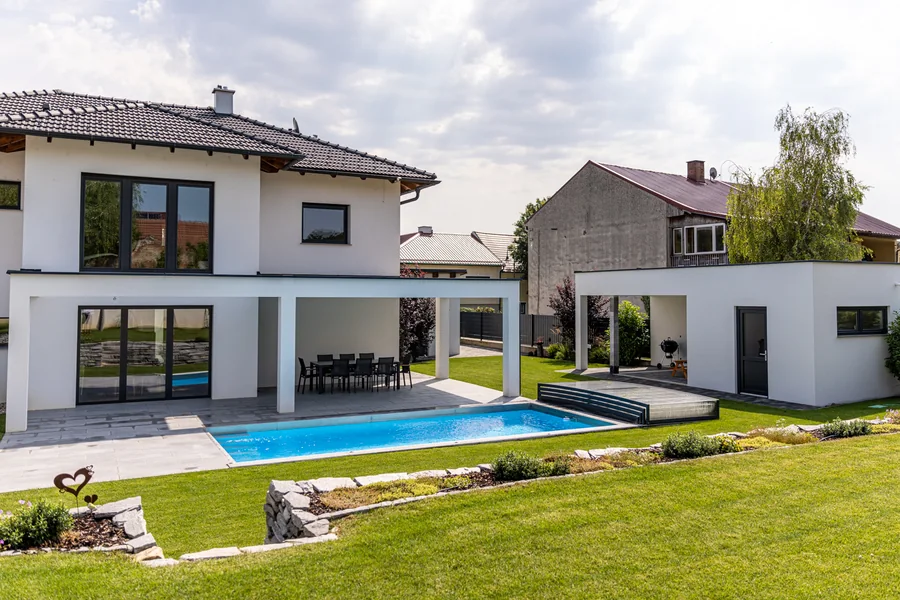 Pool mit Rasenfläche und Sitzplatz neben einem modernen Wohnhaus