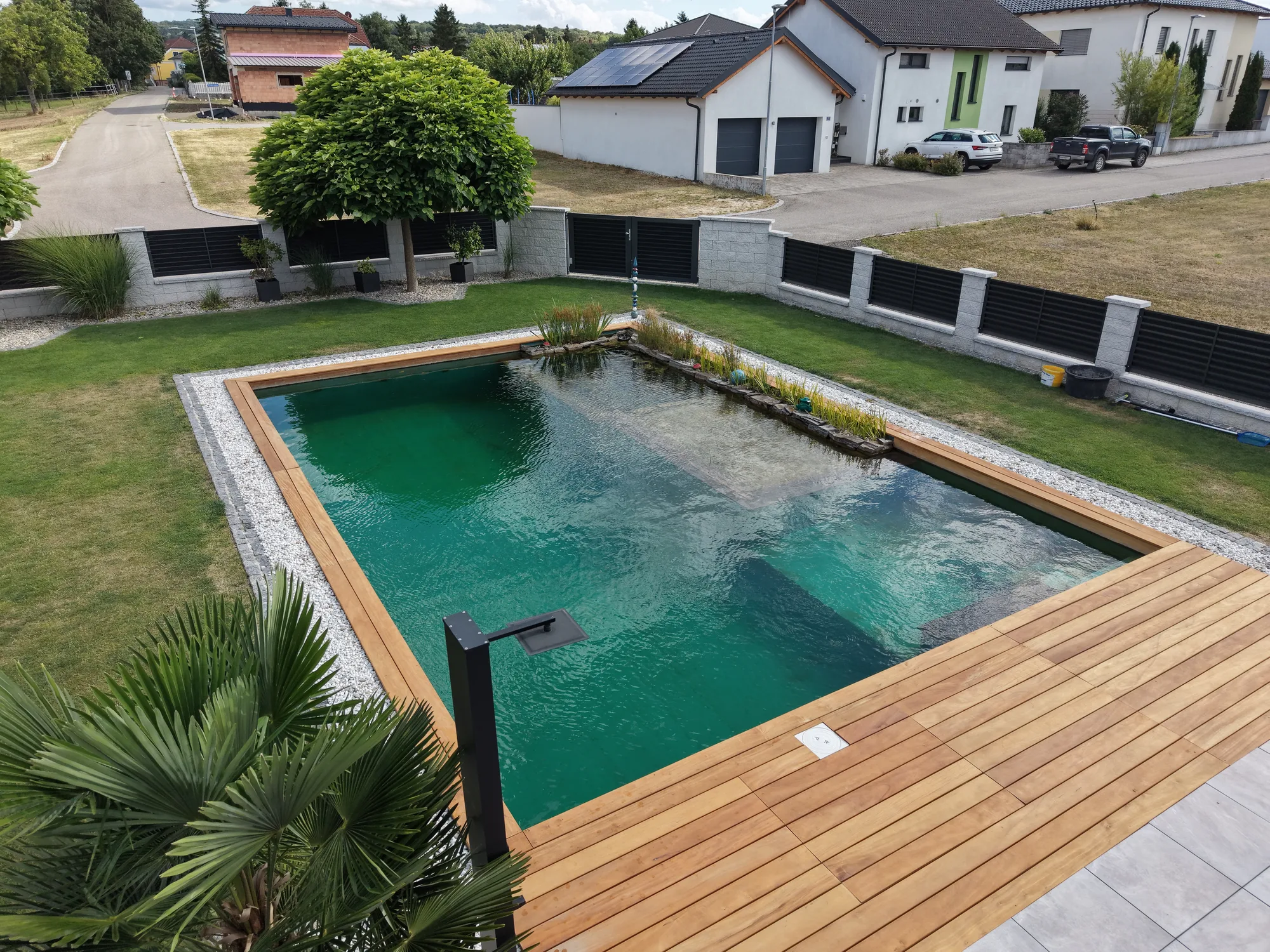 Blick von oben auf Schwimmteich und Holzdeck