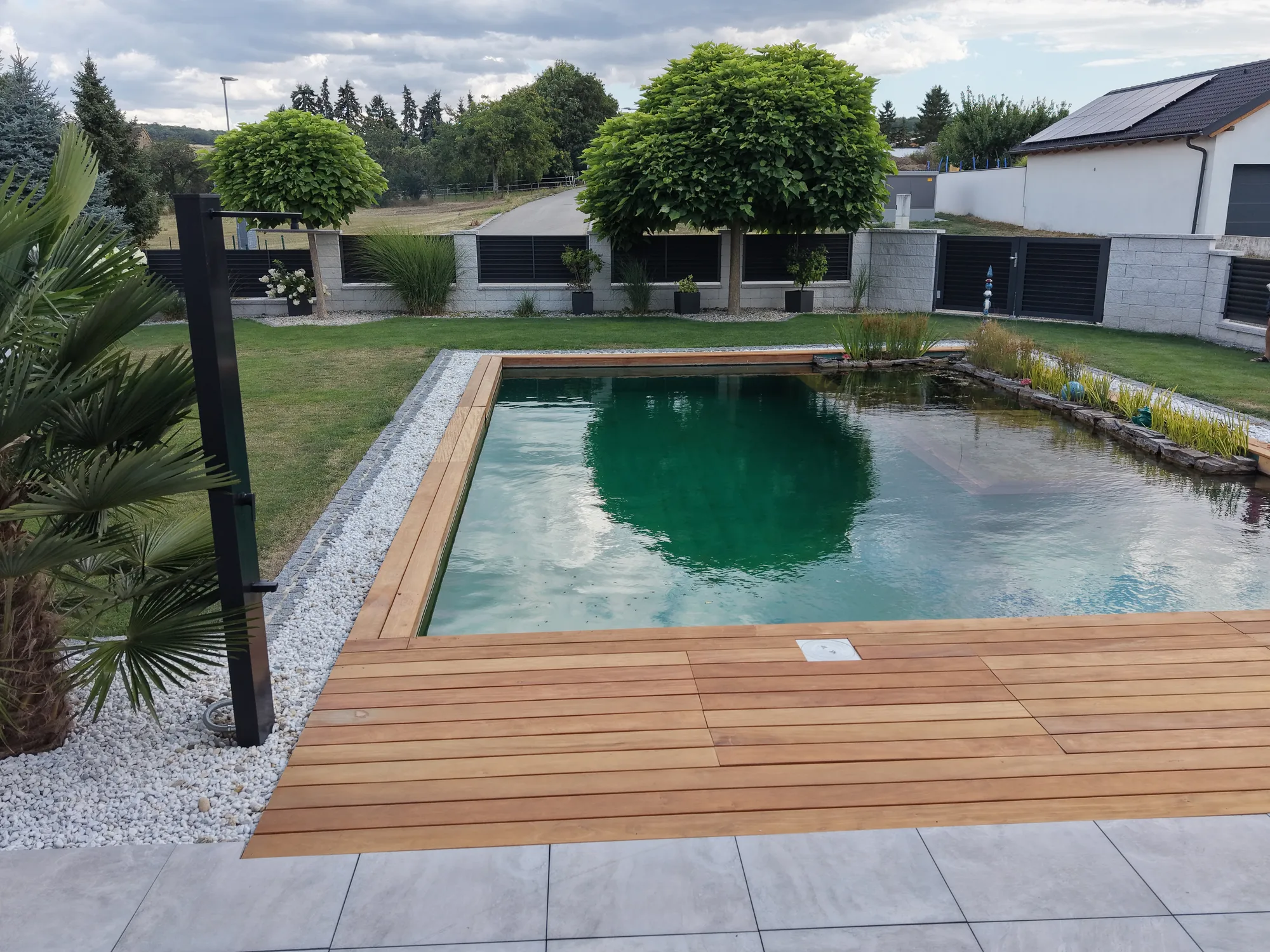 Sonnendeck aus Holz führt an die Wasserkante des Schwimmteichs