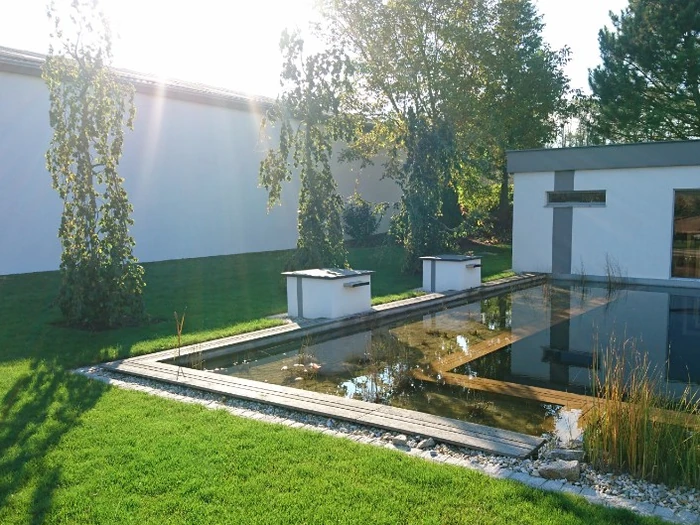 Kugelförmiges Wasserspiel aus Stein am Rand des Schwimmteichs der Schauanlage