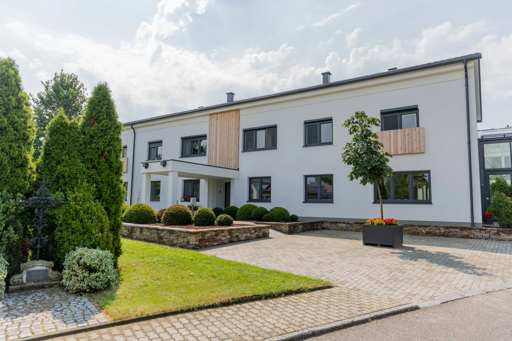 Vorgarten mit geschnittenen Formgehölzen vor dem Betriebsgebäude