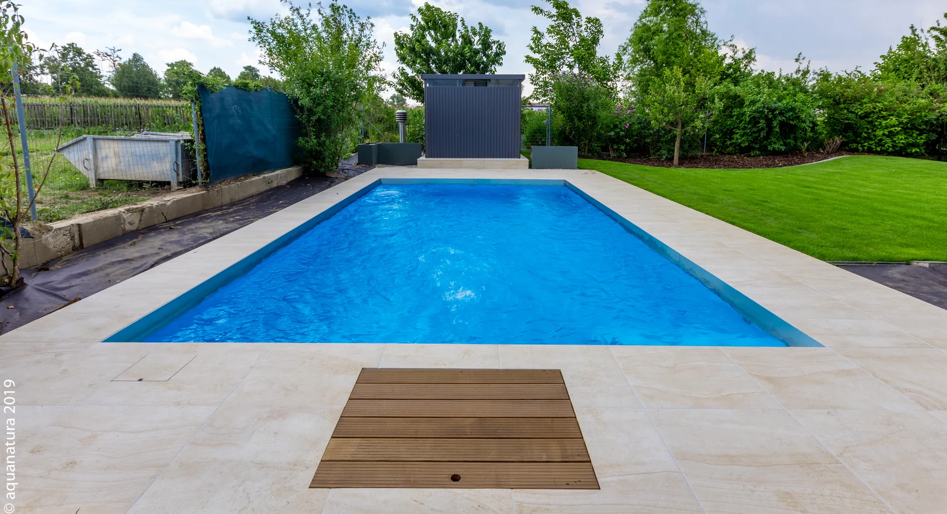 Pool mit transparenter Rollabdeckung neben einem modernen Nebengebäude